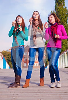 Three young beautiful women blow bubbles