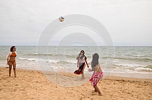 Three young and beautiful women playing boley on the shore of the beach. The women are enjoying the game and their day at the