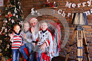 Three young boys tell Santa Claus funny stories in decorated in