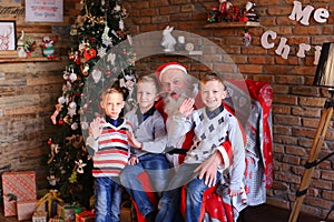 Three young boys tell Santa Claus funny stories in decorated in