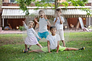 Three young boys and toddler girl making funny faces outdoors.