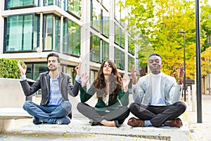 Three young business people doing yoga excercises during a break