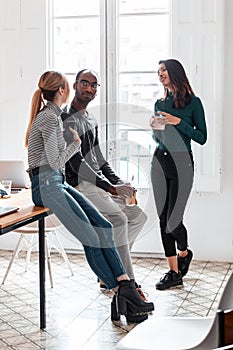 Three young business people drinking coffee while taking a break in the office