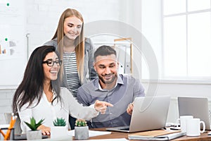 Three young business people looking at laptop