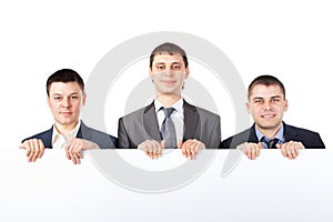 Three young businessmen hold up a large blank sign