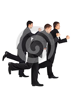 Three young businessmen run, side view