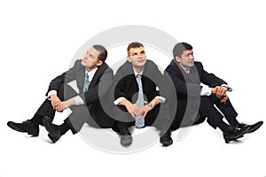 Three young businessmen sit on floor