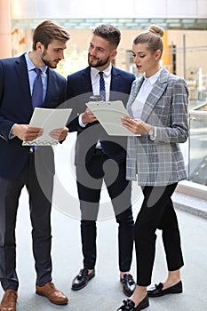 Three young businessmen standing discussing business at an office meeting.