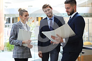 Three young businessmen standing discussing business at an office meeting