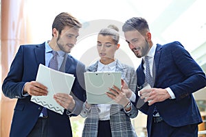 Three young businessmen standing discussing business at an office meeting