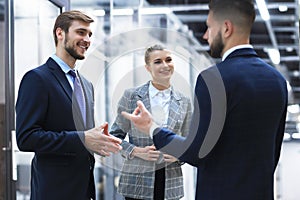 Three young businessmen standing discussing business at an office meeting.