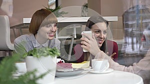 Three young caucasian girls are sitting in a cafe, laughing, smiling, friends, company, gossips, dialogue, discussion