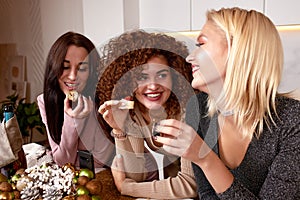 Three young cheerful intercultural women with alcoholic drinks standing in front of camera while enjoying home party in