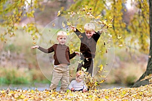 Three Young Children playing in Fallen Leaves