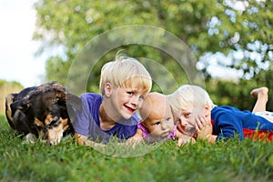 Three Young CHildren Relaxing Outside with Pet Dog