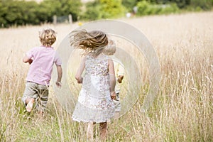 Three young children running outdoors