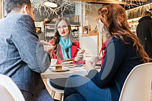 Three young colleagues relaxing during coffee break in a trendy cafeteria