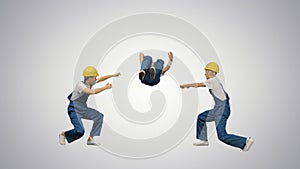 Three young construction workers in hard hats synch dancing look