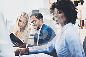 Three young coworkers working together in a modern office.Man wearing glasses and discussing with colleague new