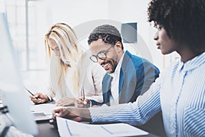 Three young coworkers working together in a modern office.Man wearing glasses and making notes with colleague on