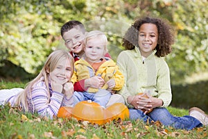 Three young friends with baby and pumpkins