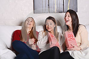 Three young friends eating popcorn and watching movies.