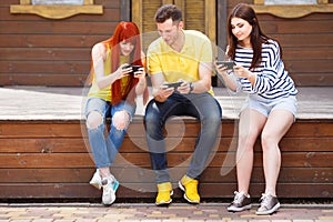 Three young friends laughing watching video on mobile phone outd