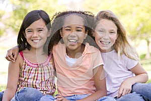 Three young girl friends sitting outdoors