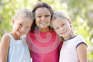 Three young girl friends standing outdoors smiling