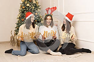 Three young girls hold in hands wooden letters a happy new year and look in the camera