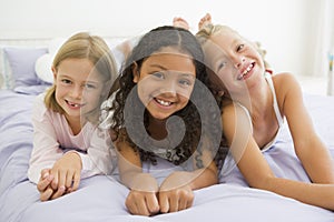 Three Young Girls Lying On A Bed In Their Pajamas