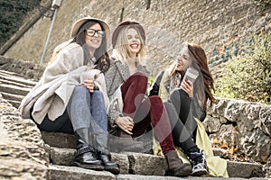 Three young girls sitting on the stairs at the public park.