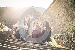 Three young girls sitting on the stairs at the public park.