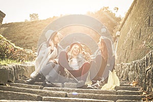 Three young girls sitting on the stairs at the public park.