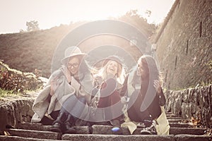 Three young girls sitting on the stairs at the public park.