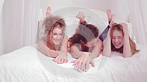 Three young girls smiling at camera. Free time concept. Happy friends girl gossip and have fun during a slumber party