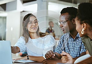 Three young happy businesspeople having a meeting while sitting at a table and working on a laptop at work. Business