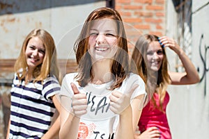 Three young happy teenage girls showing thumb up