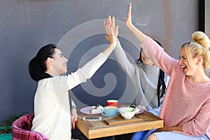 Three young lovely girls girlfriends chatter, rejoice, high five