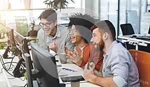 Three young men enjoying good coding job on computer