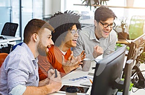 Three young men enjoying good coding job on computer
