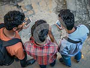 Three young men look down at their phones