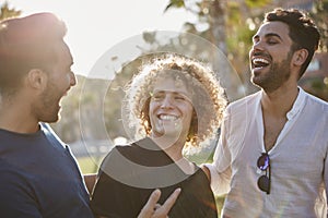 Three young men standing together outside laughing