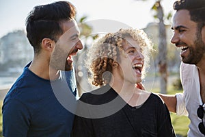 Three young men talking together outside laughing