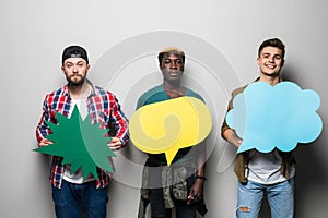 Three young mixed race men friends with speech bubbles isolated on gray background
