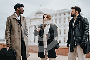 Three young people discuss work while standing together in an urban setting, embodying the dynamic of remote business