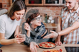 Three young people sitting around, laughing, talking and taking