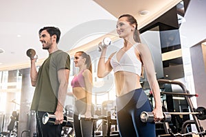 Three young people smiling while alternating dumbbell bicep curl