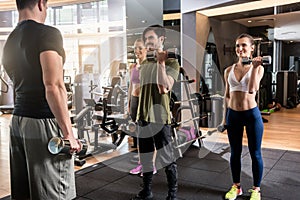 Three young people smiling while alternating dumbbell bicep curl