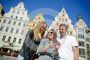 Three young people stand on the square of the ancient city.